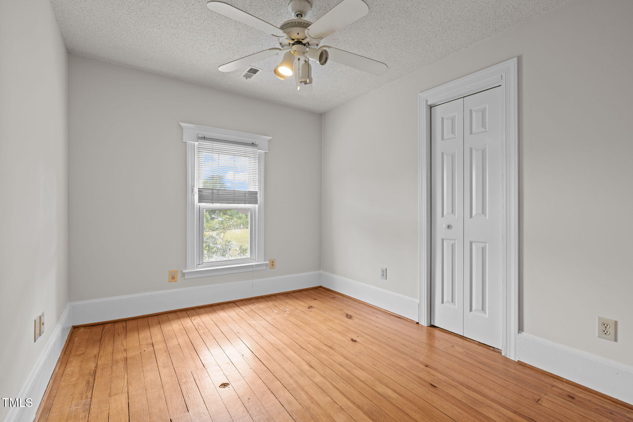 504 Parks Village Road Zebulon, NC 27597 - Photo 28 of 50 an empty room with wooden floor chandelier fan and windows