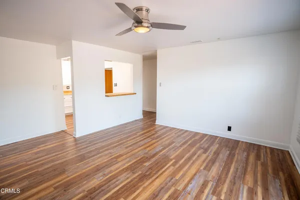 a view of an empty room with wooden floor and windows