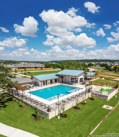 a view of a swimming pool with lawn chairs and a big yard