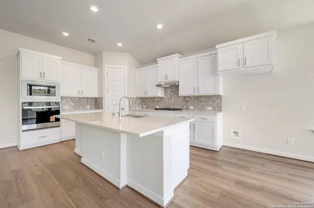 a kitchen with kitchen island granite countertop a sink cabinets and wooden floor