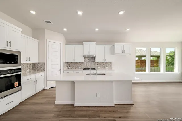 a large white kitchen with kitchen island a sink a stove and a refrigerator