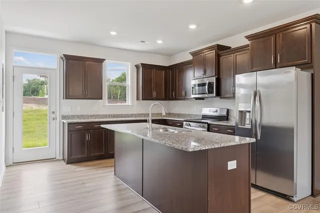 a kitchen with stainless steel appliances granite countertop a refrigerator a sink a stove a microwave and wooden cabinets