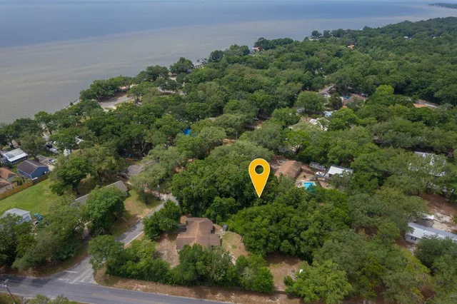 an aerial view of a house with outdoor space and trees all around