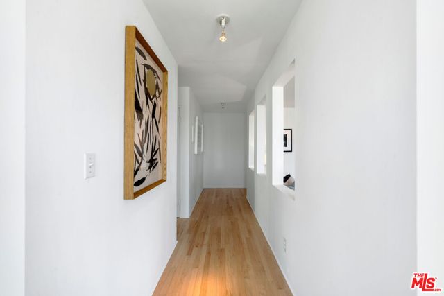 a view of a hallway with wooden floor and a bathroom
