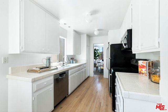 a kitchen with a sink a counter top space stainless steel appliances and cabinets