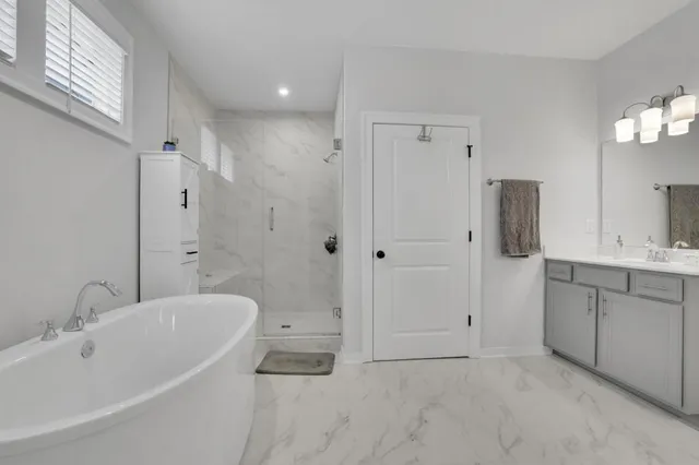 a bathroom with a tub shower sink and mirror