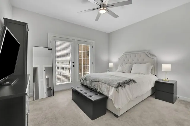 a spacious bedroom with a bed and a flat tv screen on the dresser