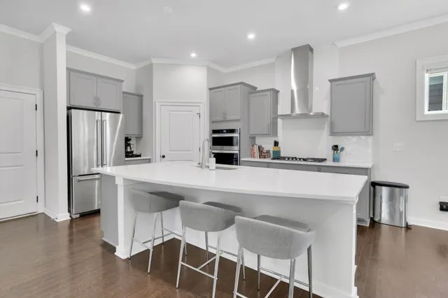 a kitchen with stainless steel appliances a dining table chairs refrigerator and sink