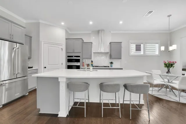 a kitchen with stainless steel appliances a dining table chairs refrigerator and sink