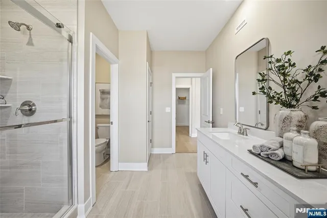 a large white bathroom with a granite countertop sink a mirror and shower
