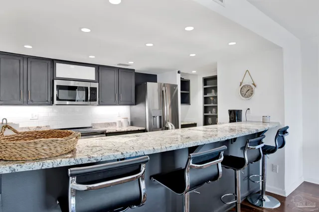 a kitchen with granite countertop kitchen island stainless steel appliances and wooden cabinets