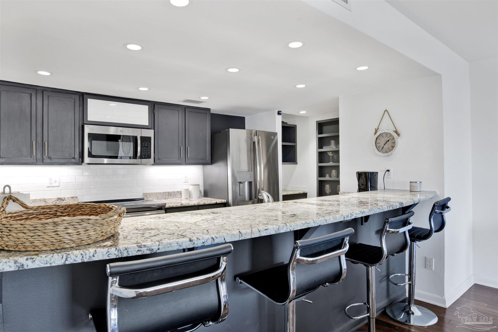 16784 Perdido Key Drive, Unit 9 Pensacola, FL 32507 - Photo 9 of 48 a kitchen with granite countertop kitchen island stainless steel appliances and wooden cabinets