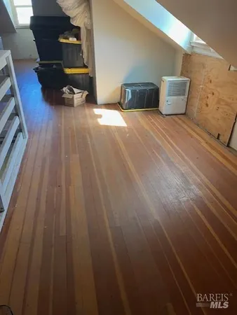 a view of kitchen and empty room with wooden floor