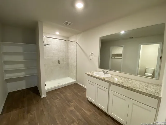 a bathroom with a granite countertop sink a toilet and shower