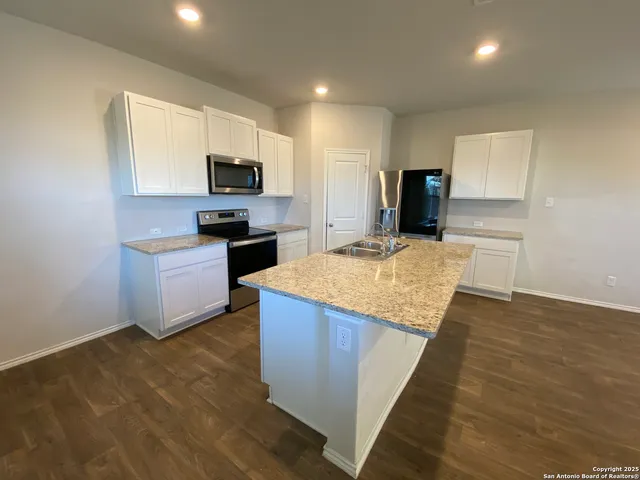 a kitchen with stainless steel appliances granite countertop a stove top oven a sink dishwasher and a refrigerator