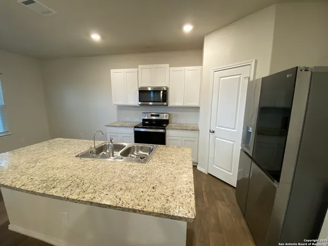 a kitchen with stainless steel appliances granite countertop a refrigerator a stove and a sink