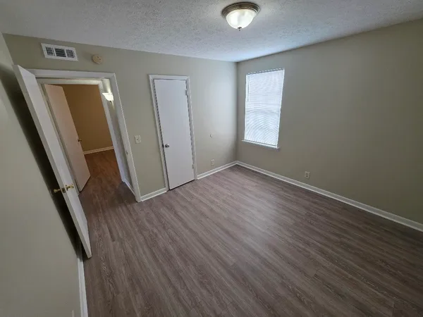 an empty room with wooden floor and windows