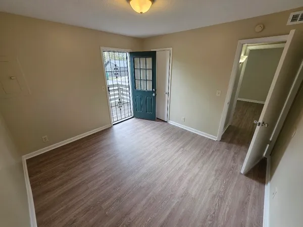 an empty room with wooden floor and windows