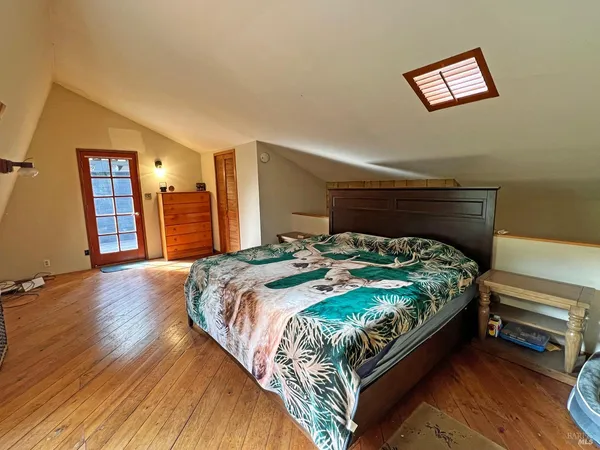 a bed sitting in a bedroom next to a window and a chair