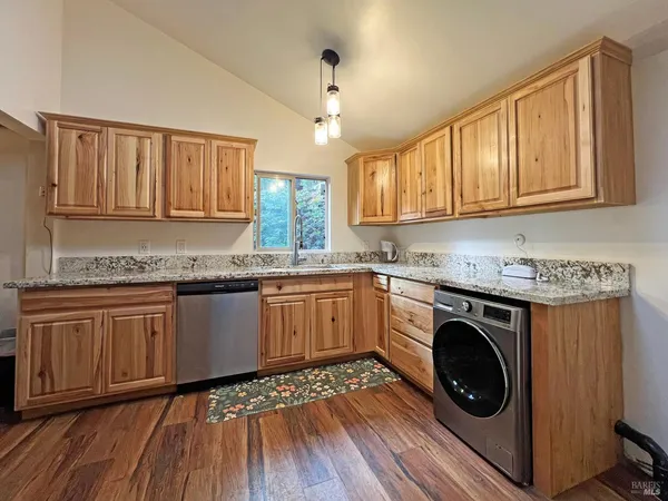 a kitchen with granite countertop a sink cabinets stainless steel appliances and a window
