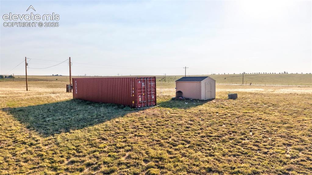 9670 Boone Road Yoder, CO 80864 - Photo 18 of 18 Expansive open land featuring a red shipping container and a tan storage shed