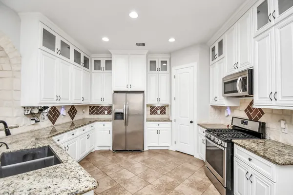 a kitchen with stainless steel appliances granite countertop a refrigerator and a stove top oven