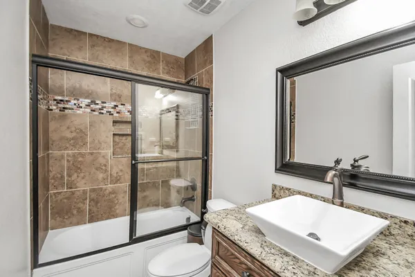 a bathroom with a granite countertop sink a toilet and shower