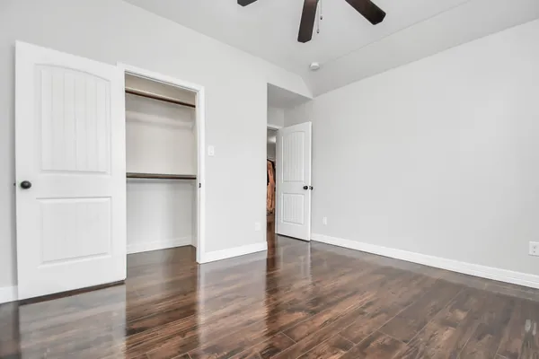 a view of an empty room with a ceiling fan and wooden floor