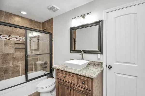 a bathroom with a granite countertop sink toilet and shower