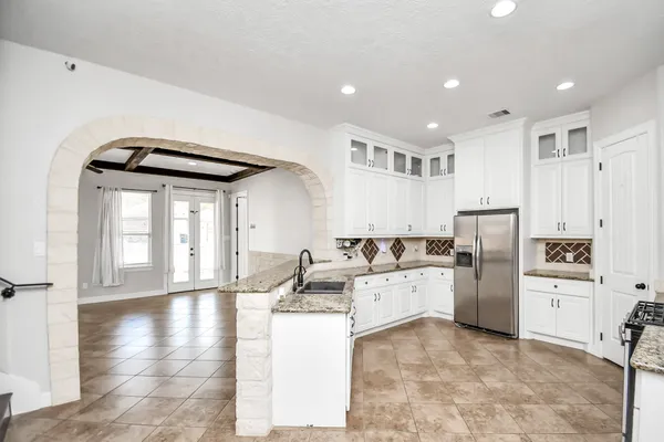 a kitchen with stainless steel appliances granite countertop a refrigerator a stove and a wooden floors