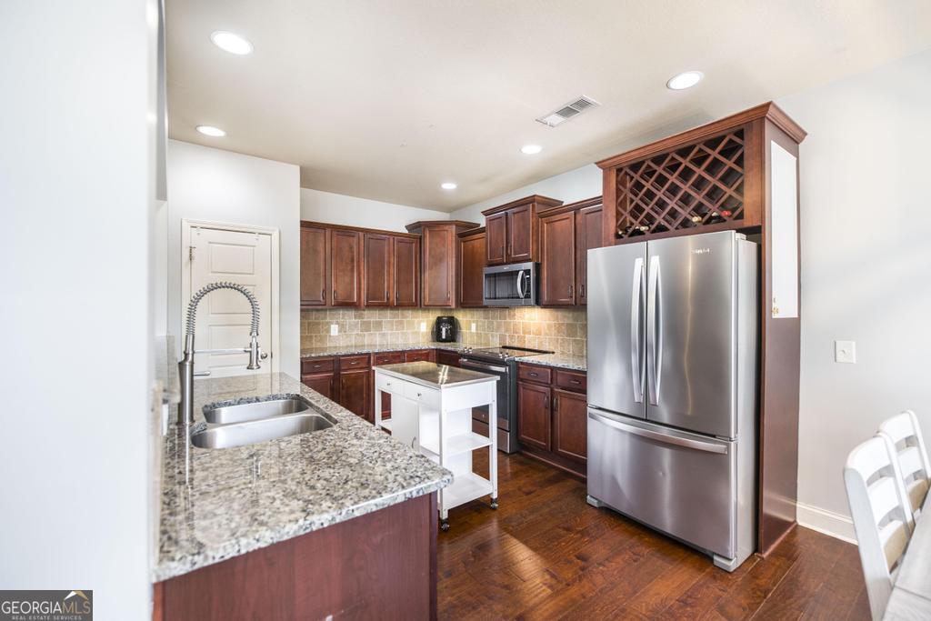 400 Ansley Avenue Perry, GA 31069 - Photo 13 of 37 a kitchen with stainless steel appliances granite countertop a refrigerator a stove and a sink with wooden floor