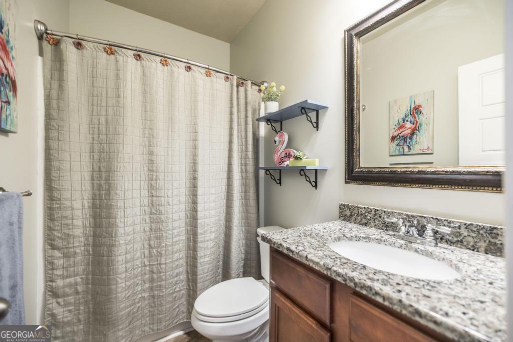 400 Ansley Avenue Perry, GA 31069 - Photo 17 of 37 a bathroom with a granite countertop sink a toilet and a shower curtain