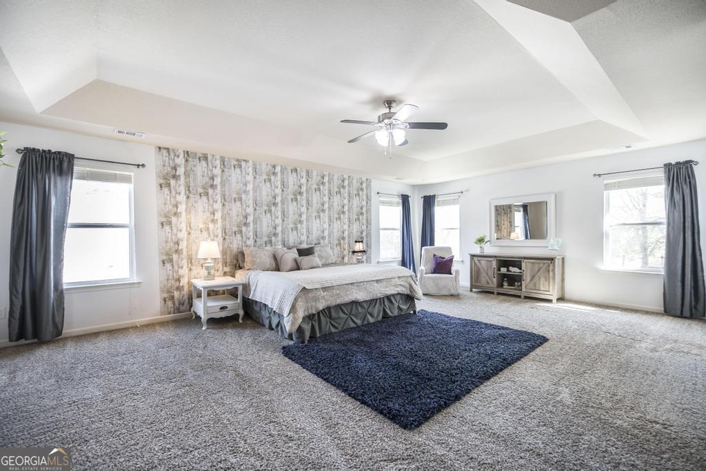 400 Ansley Avenue Perry, GA 31069 - Photo 26 of 37 a spacious bedroom with a large bed a chandelier and windows