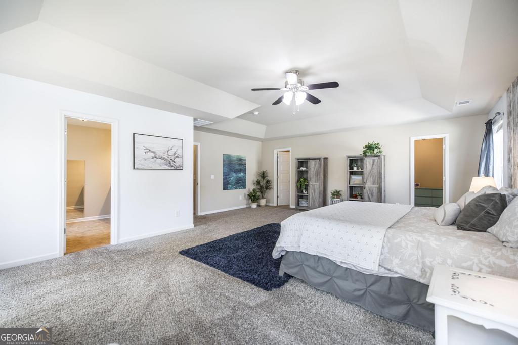 400 Ansley Avenue Perry, GA 31069 - Photo 27 of 37 a spacious bedroom with a large bed a chandelier and closet