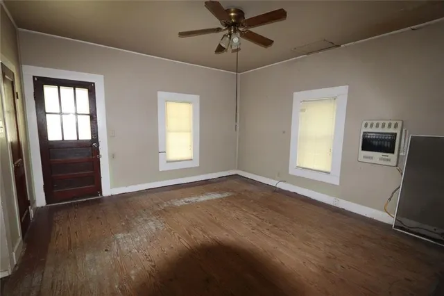 a view of an empty room with a window and wooden floor