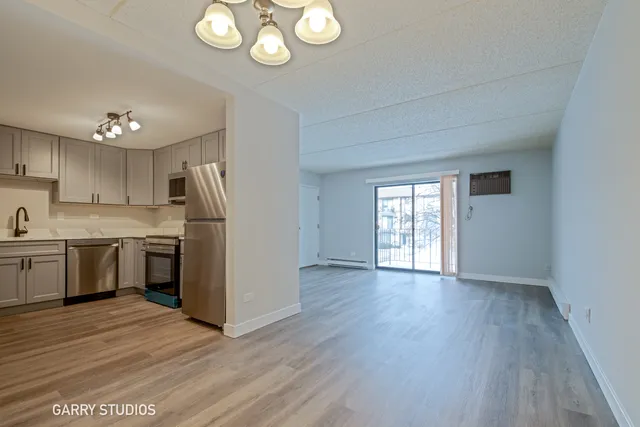 a kitchen with stainless steel appliances granite countertop a refrigerator a sink dishwasher a stove and white countertops with wooden floor