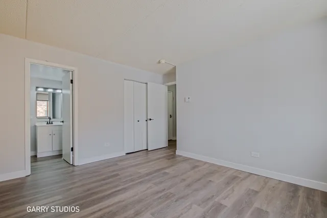 a view of an empty room with wooden floor and closet