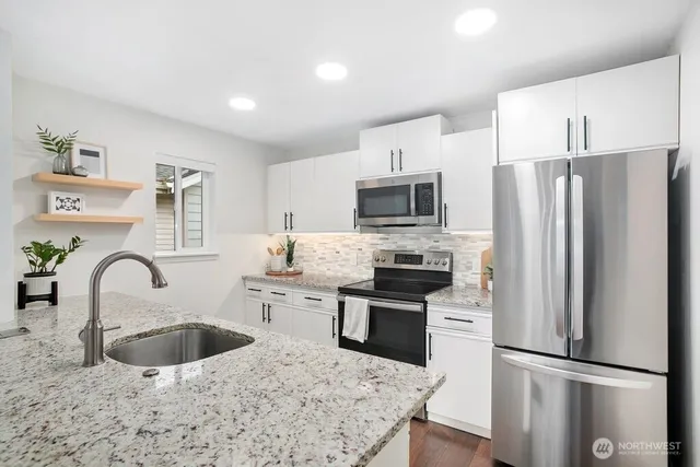 a kitchen with stainless steel appliances granite countertop a refrigerator sink and stove