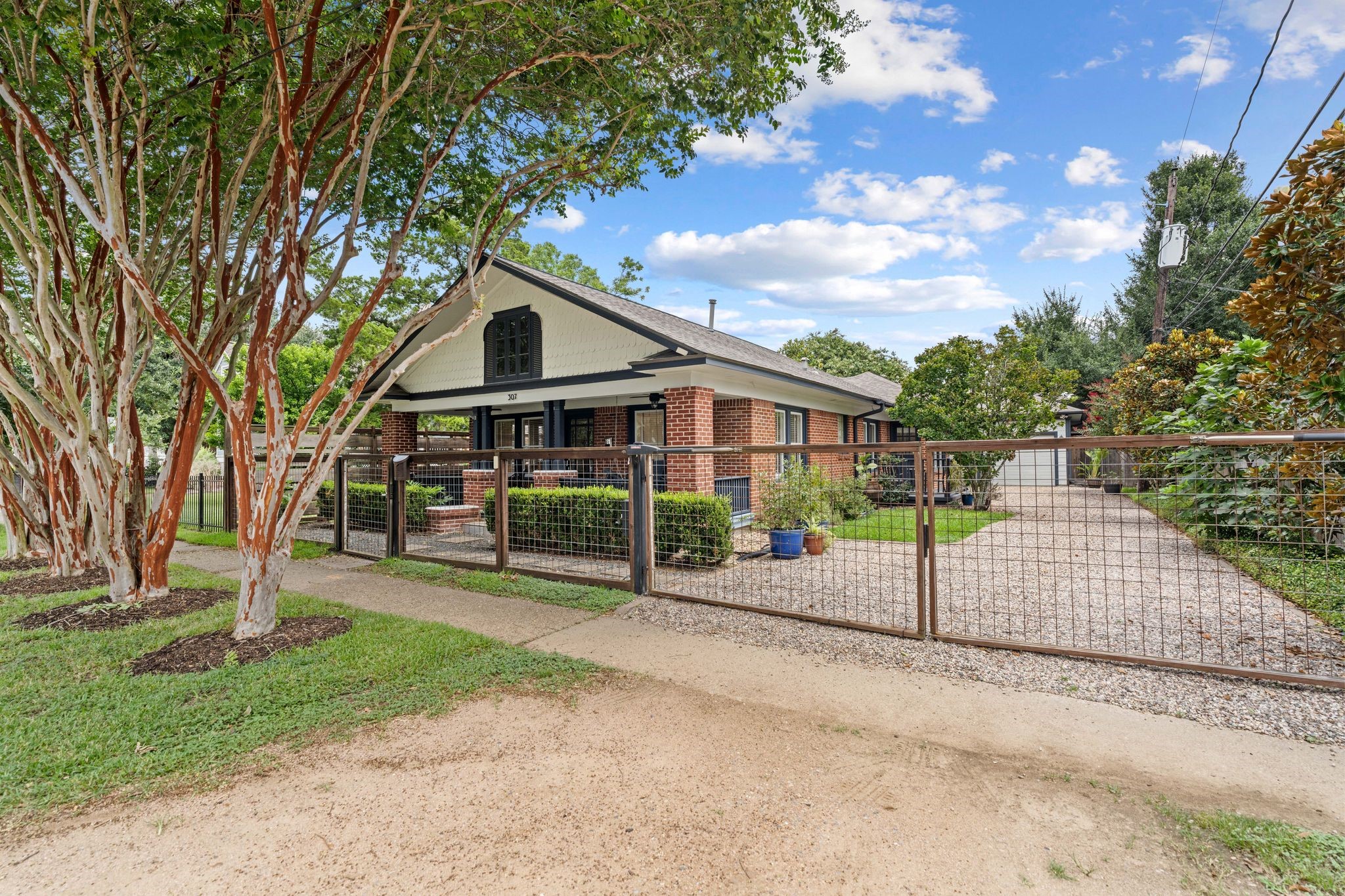 307 East 8th Street Houston, TX 77007 - Photo 2 of 35 Exceptional curb appeal featuring a red brick exterior with painted siding accents. Mature crepe myrtles out front + lush landscaping and trees lining the driveway for added privacy. Fully fenced with electronic gate & long driveway to 1 car garage.