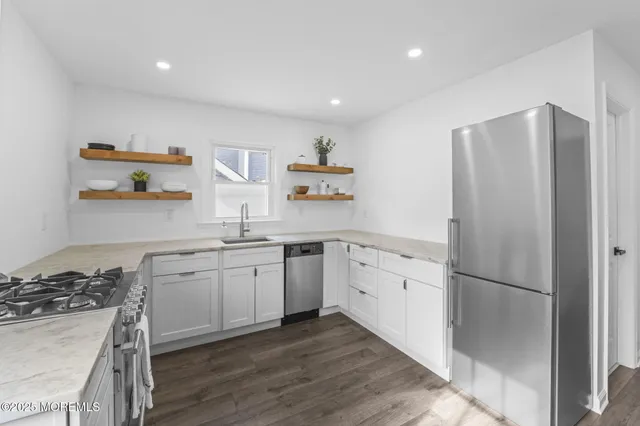 a kitchen with granite countertop a refrigerator stove top oven and sink