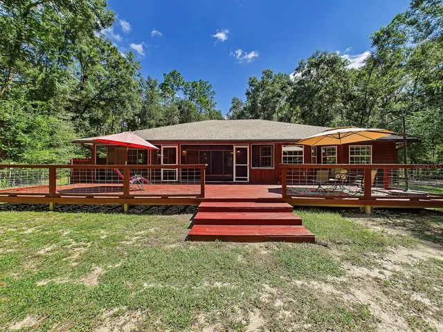 a childrens park with large trees and a wooden fence
