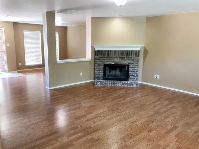 an empty room with wooden floor a fireplace and entryway
