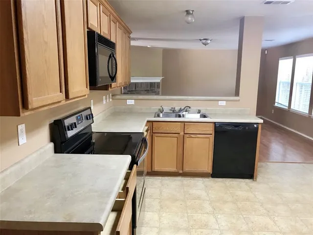 a kitchen with stainless steel appliances a sink a stove a microwave a counter top space and cabinets