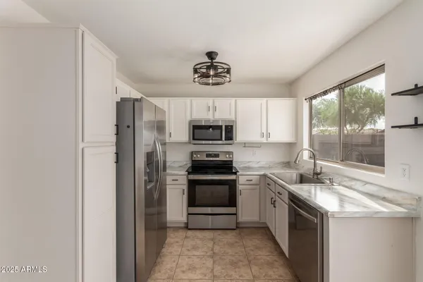 a kitchen with granite countertop a sink stainless steel appliances and window