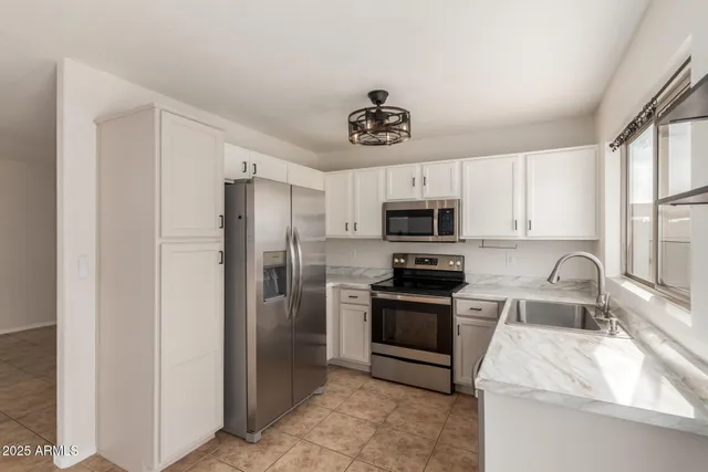 a kitchen with stainless steel appliances granite countertop a refrigerator a stove a sink and a microwave