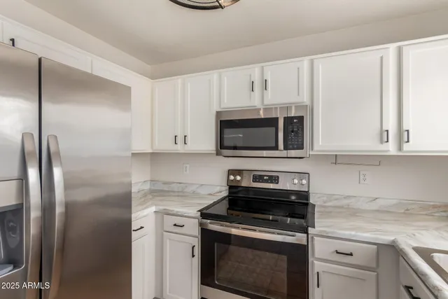 a kitchen with white cabinets and stainless steel appliances