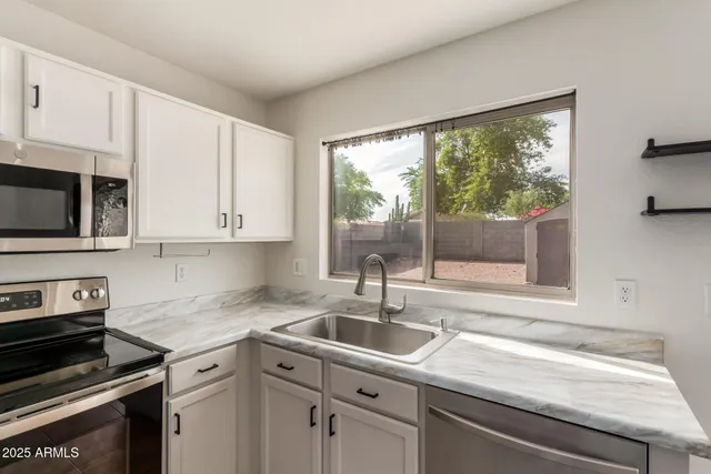 a kitchen with granite countertop a sink stove top oven and cabinets