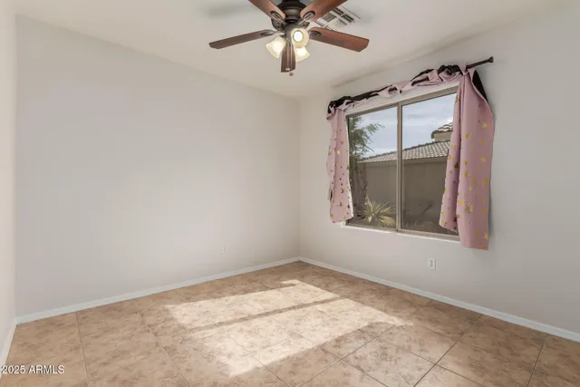 an empty room with a ceiling fan and carpet