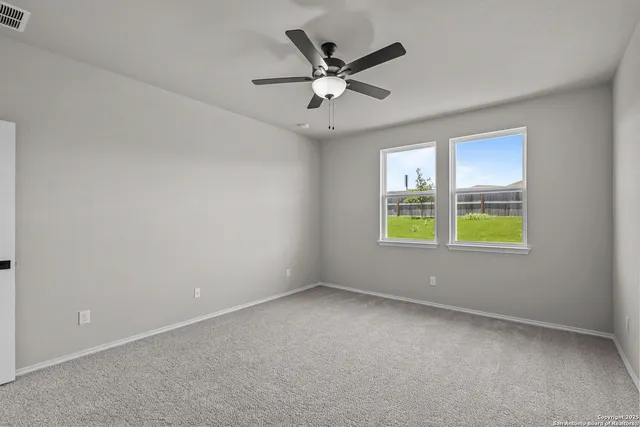 an empty room with windows and ceiling fan