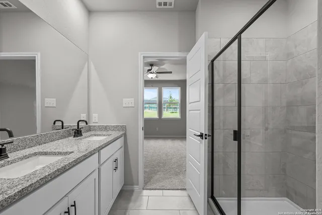 a bathroom with a granite countertop sink a mirror and shower